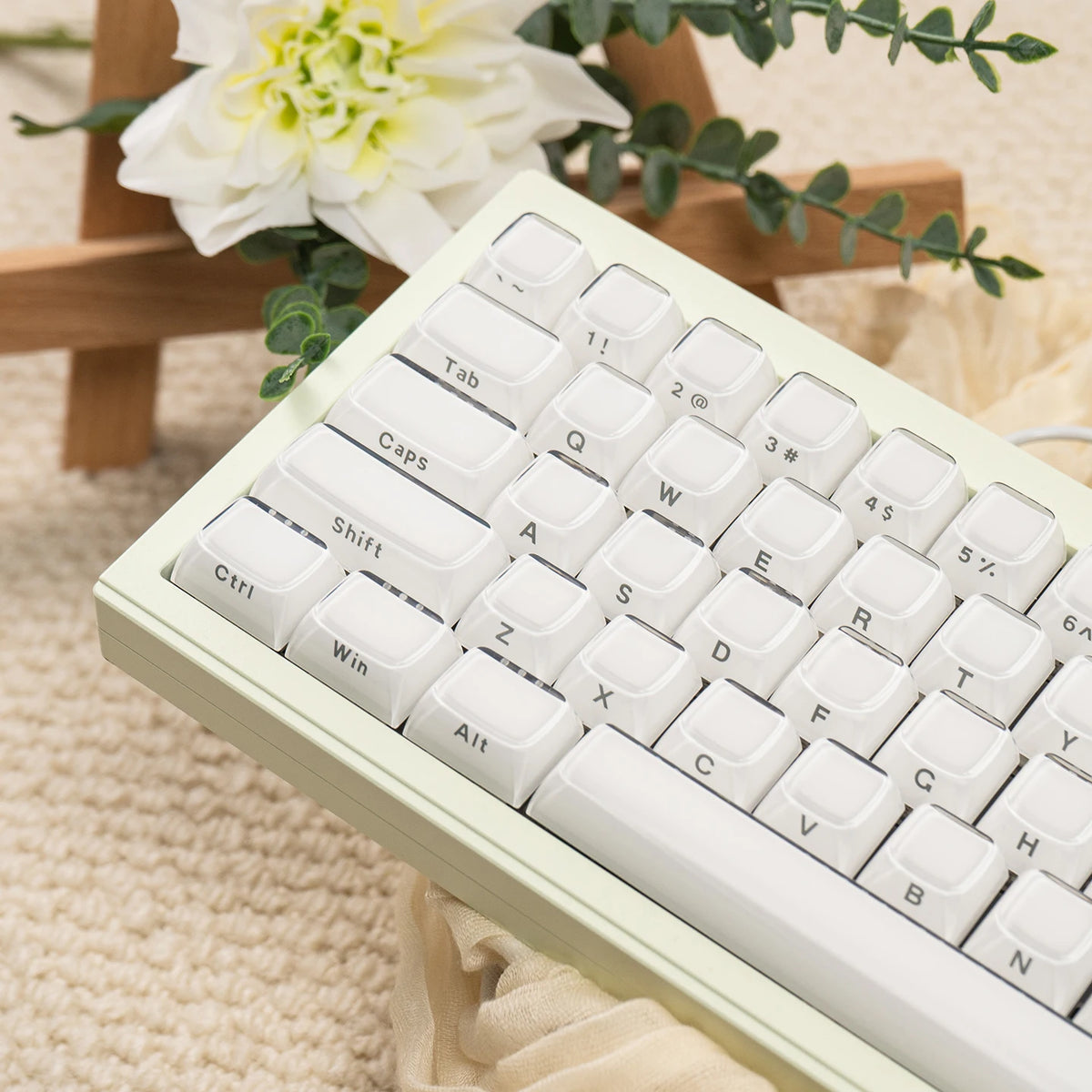 A close-up view of a white mechanical keyboard with custom printed jelly keycaps resting on a beige knitted surface.