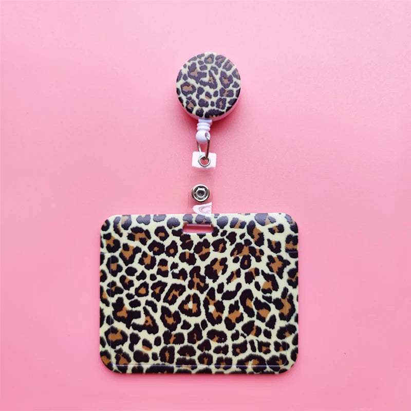 A leopard print ID holder with a matching lanyard and keychain displayed on a pink background.