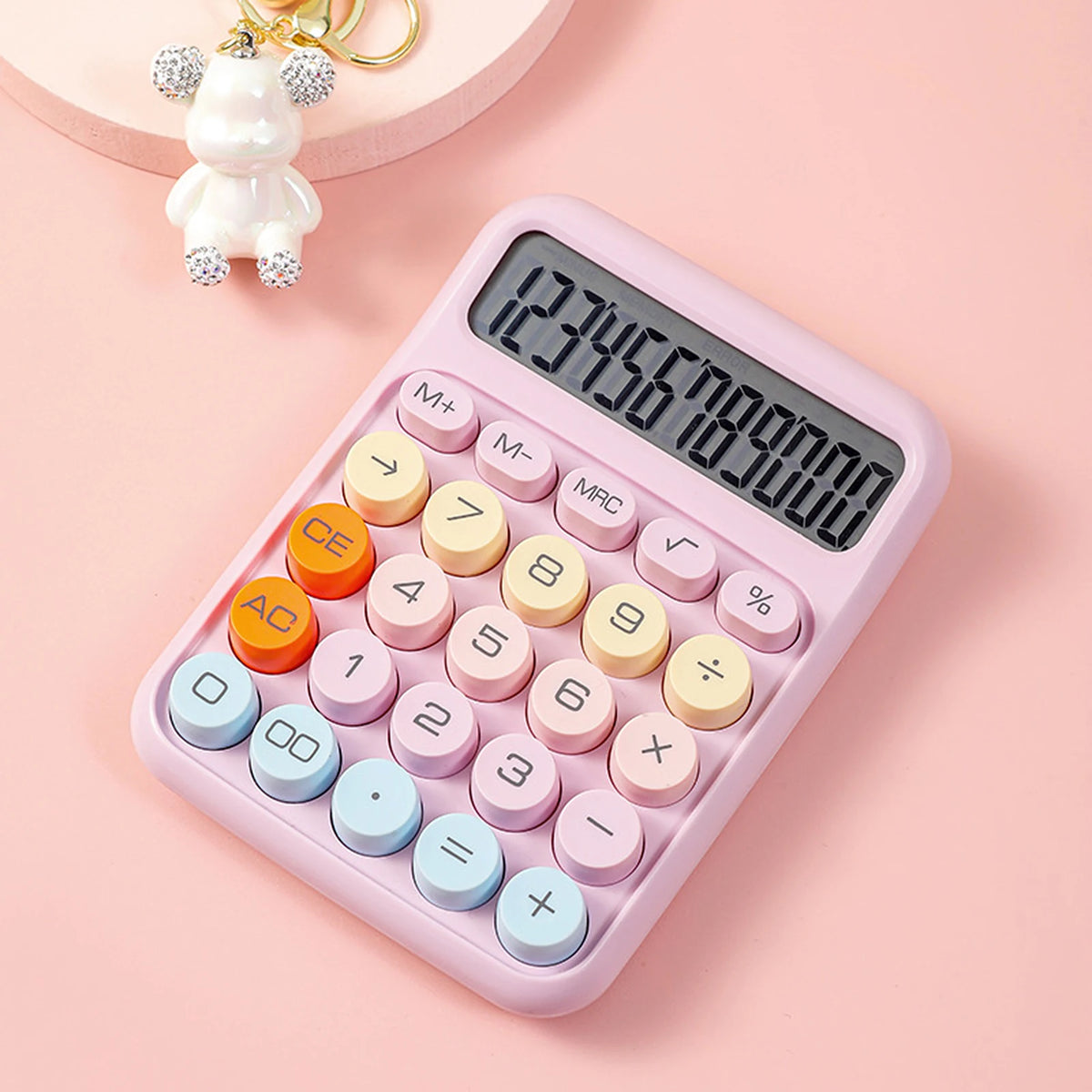 A pink mechanical 12-digit calculator with round keys is shown on a light pink background.