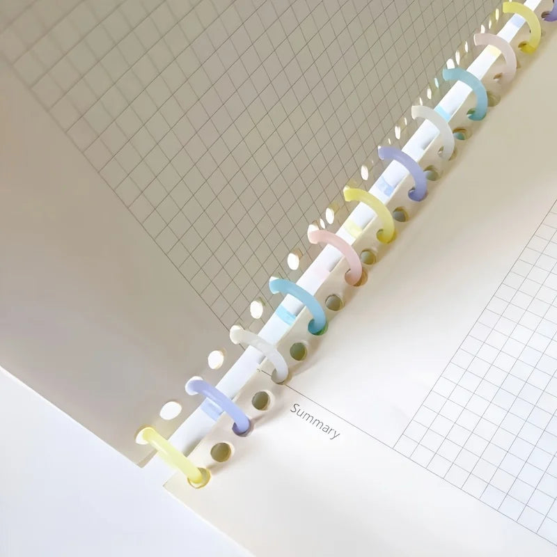 A close-up view of colorful reusable plastic binding rings along the edge of a spiral-bound notebook page.