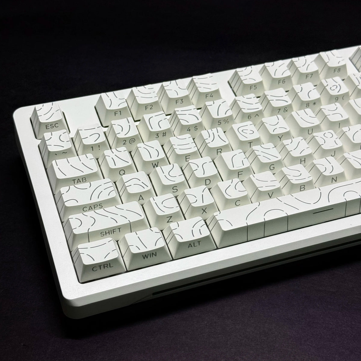 Vista cercana de un teclado mecánico blanco con teclas degradadas de contorno sobre una superficie oscura.