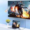 A laptop is placed in front of a large monitor displaying an action scene, with a 3-in-1 USB-C to HDMI docking adapter visibl