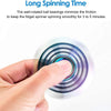 A hand is spinning a rainbow metal fidget spinner, showing the rotating layers of the device.