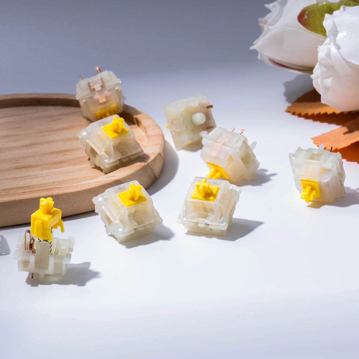 A collection of milky yellow Pro Hotswap mechanical keyboard switches scattered on a white surface.
