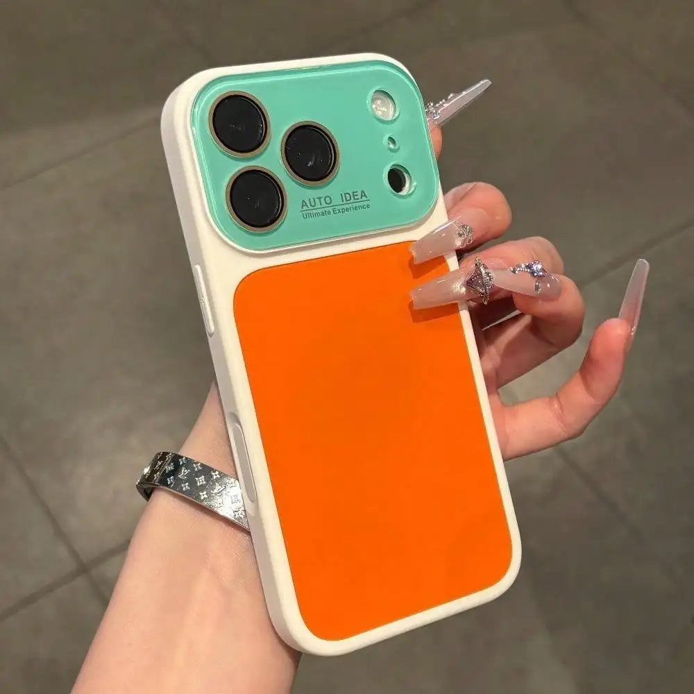 A hand holds an orange color block phone case with a white frame and a clear green back, featuring multiple camera lenses.