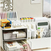 A hand is shown interacting with a white desk organizer featuring multiple clear storage drawers for office supplies.