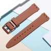 A brown silicone watch strap is shown with replacement tools, laid out on a light background.
