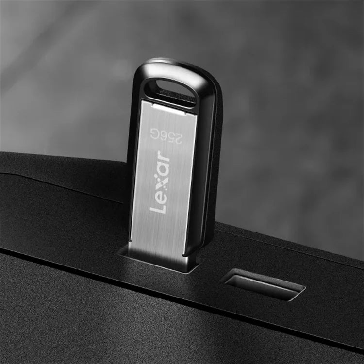 A close-up of a silver Lexar USB flash drive inserted into a black device slot.