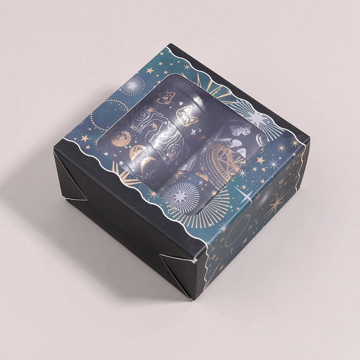 A dark box containing a metallic gold washi tape set with celestial designs and stars.