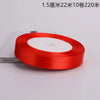 A roll of bright red satin ribbon with a white center core is shown on a white surface.