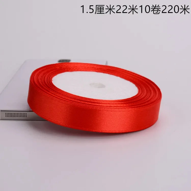 A roll of bright red satin ribbon with a white center core is shown on a white surface.