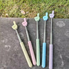 A set of five telescopic stainless steel teaching pointers with colorful silicone tips resting on a gray surface.