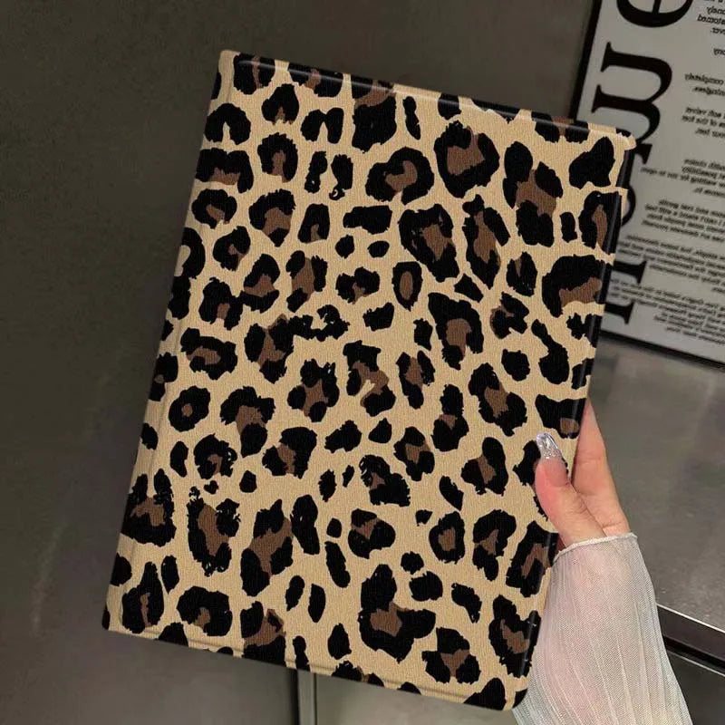A close-up of a leopard print protective skin for an iPad case being held by a hand.