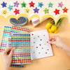 A collection of colorful glitter foil star stickers is displayed on a light background with craft supplies.
