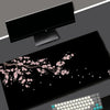 Black gaming mouse pad with a pink cherry blossom design and a white keyboard visible.