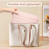 A light pink padded laptop sleeve is being placed into a beige canvas tote bag.