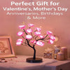 A black rose tree LED night light with pink glowing roses displayed on a white surface.