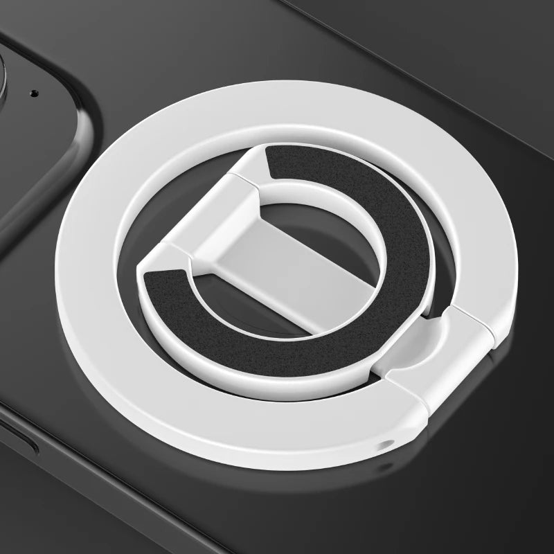 A white circular phone ring holder with a black insert is shown on a dark surface.