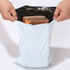Hands are holding a white self-sealing waterproof shipping bag open to reveal a rectangular piece of brown food inside.