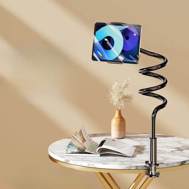 A black rotating tablet and phone stand with a flexible spiral base resting on a marble table.