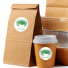 A brown paper bag and a disposable cup both feature a green tea logo sticker.
