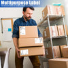A man is holding several cardboard boxes with thermal shipping labels for small business essentials.