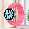 A pink knitted nylon watch strap is displayed on a silver watch, next to a window.