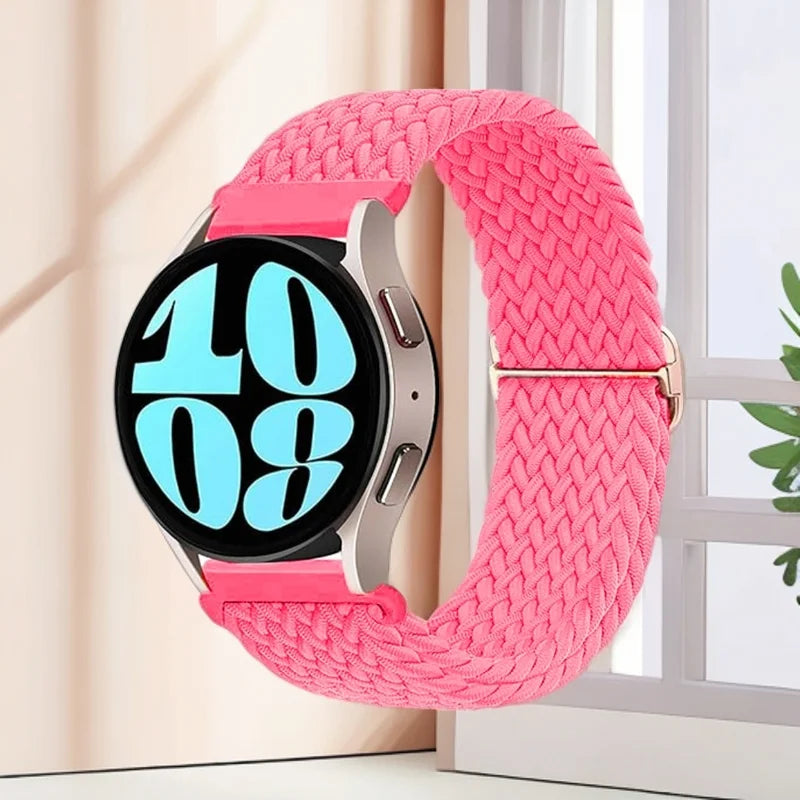 A pink knitted nylon watch strap is displayed on a silver watch, next to a window.