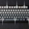 A black mechanical keyboard with a silver keycap layout is shown against a dark background.