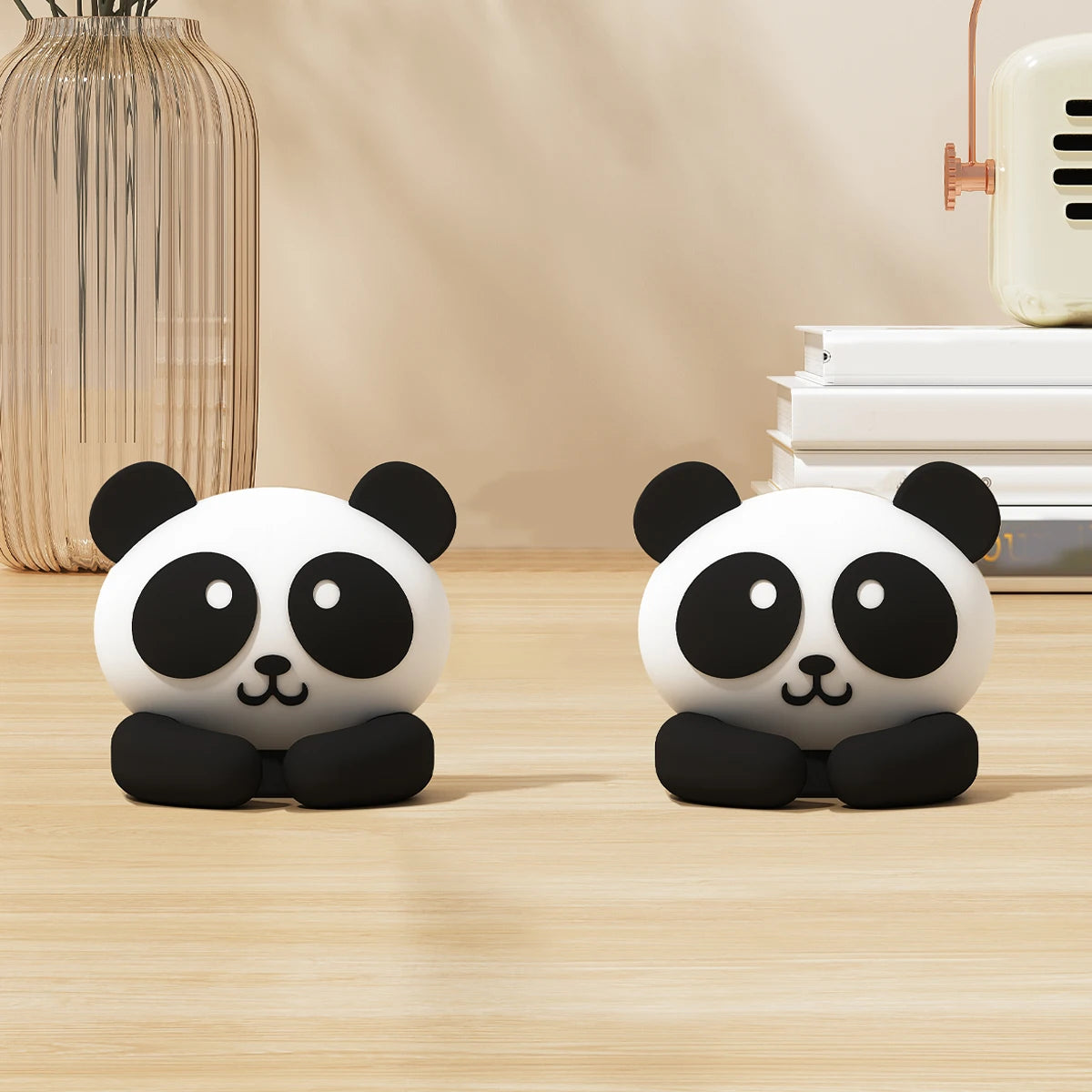 Two black and white panda desk cable organizers sitting on a wooden surface.