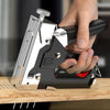 A hand is operating a silver and black 4-in-1 manual nailing gun and construction stapler set on a wooden surface.