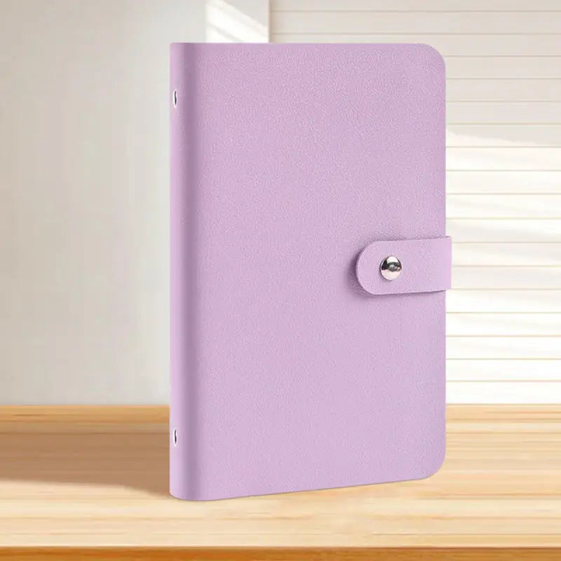 A purple reusable binder with a silver clasp resting on a wooden surface.