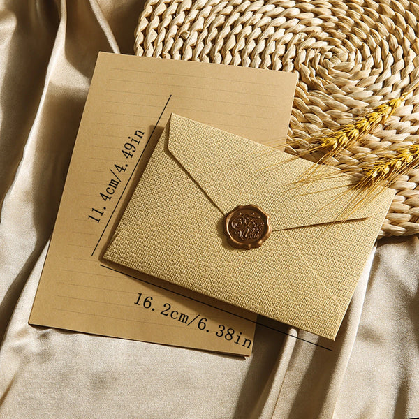 A set of beige linen envelopes and a wax seal resting on a woven mat.