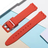 A bright orange silicone watch strap is shown next to its replacement tools on a light background.