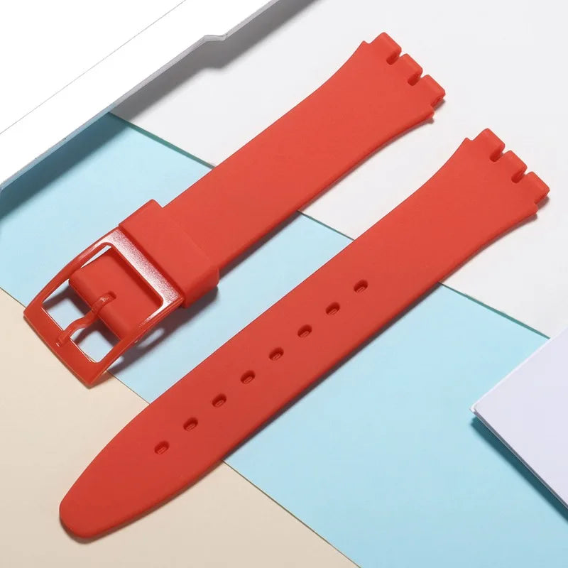A bright orange silicone watch strap is shown next to its replacement tools on a light background.