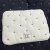 A white quilted padded laptop sleeve case with small black dots on a dark fabric background.