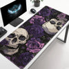 A black desk mat featuring a dark floral design with purple roses and skulls.