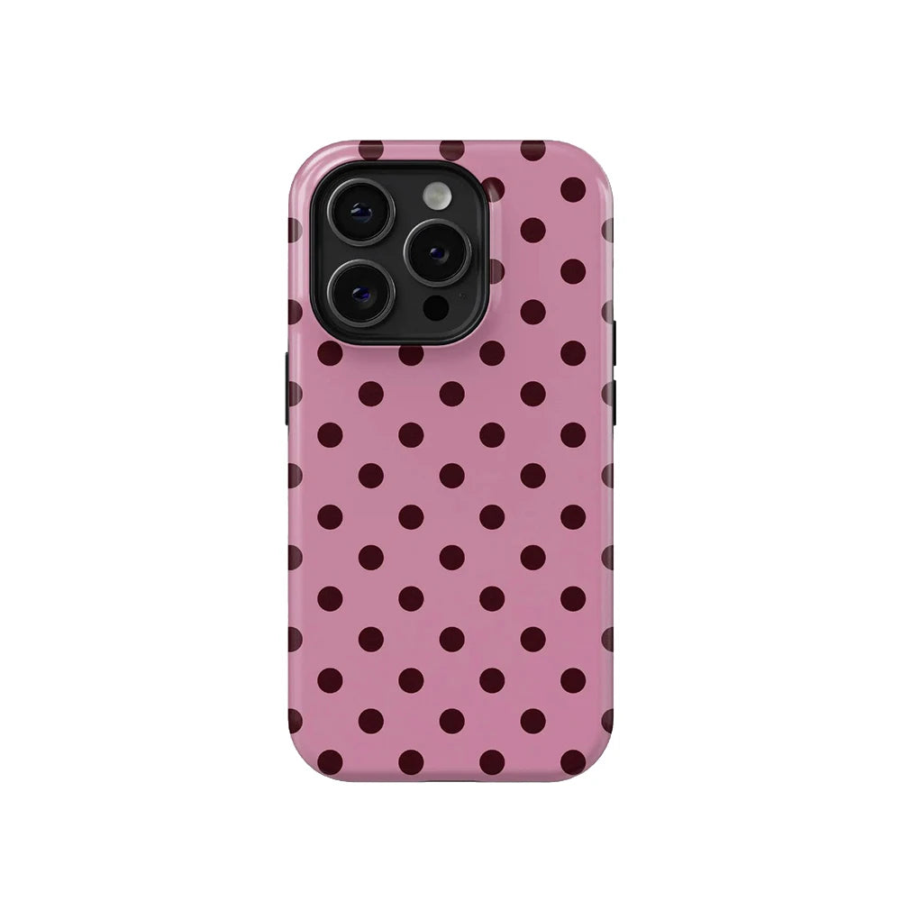 A pink phone case with a dark polka dot pattern and a clear back, featuring a camera module.