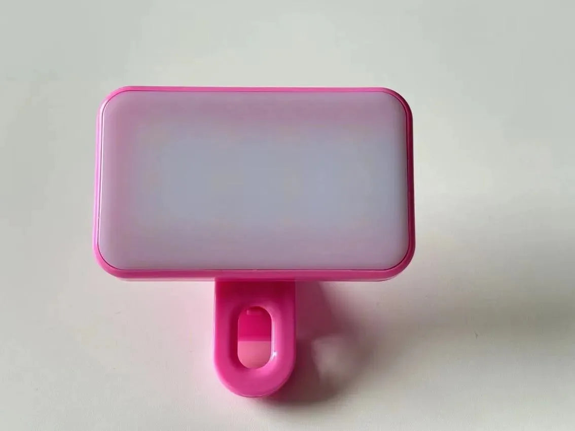 A pink portable rechargeable mini selfie light with a rectangular translucent panel and a pink clip.