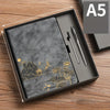 A luxury notebook set in a dark gray box featuring gold foil designs and a black pen.