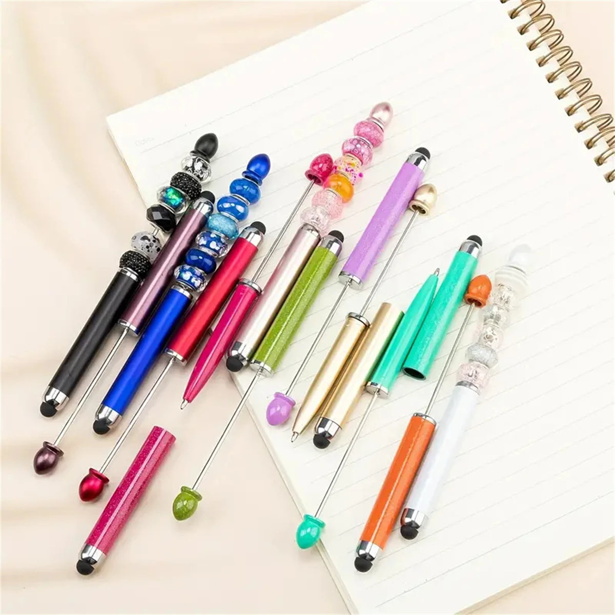 A collection of colorful beaded rubber touch ballpoint pens arranged on a white lined notepad.