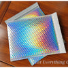 Rainbow foil bubble mailers stacked on a wooden surface