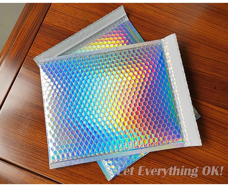 Rainbow foil bubble mailers stacked on a wooden surface