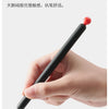 A hand is holding a black smooth gel pen with a red tip, demonstrating its use.