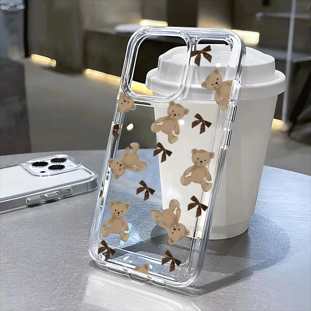 A clear plastic phone case with a floral pattern featuring small teddy bears rests on a light surface.