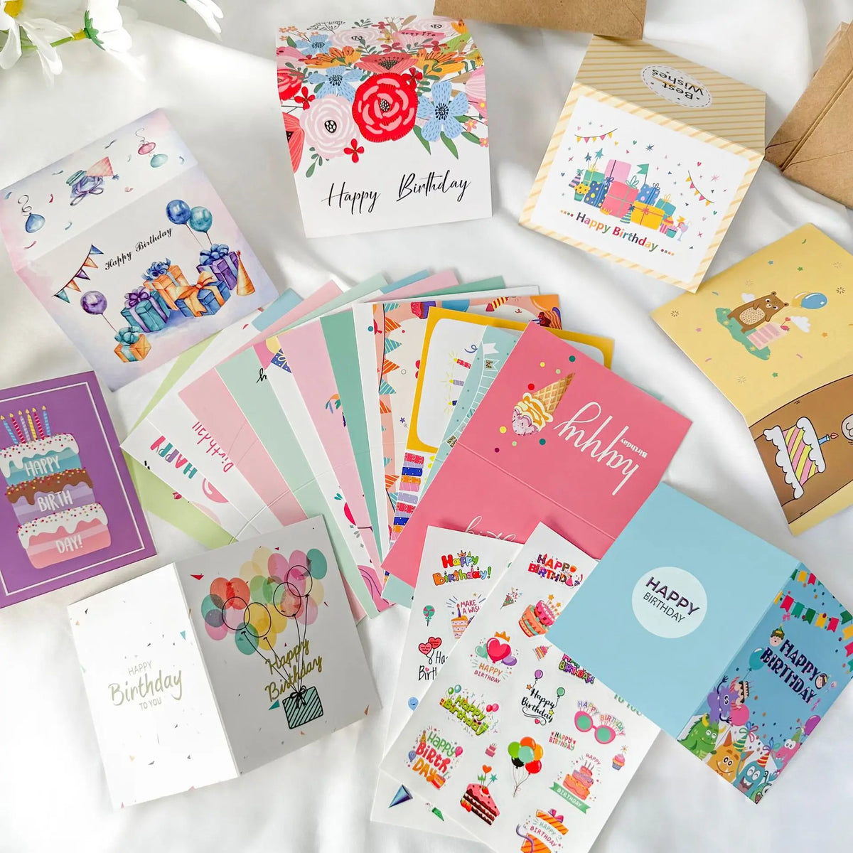 Eine Sammlung farbenfroher handgeschriebener Geburtstagskarten in verschiedenen Designs und Farben, arrangiert auf einer weiß