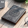A dark gray retro PU leather pocket notebook with an embossed circular design resting on a wooden surface.