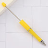 A yellow DIY beadable pen with a silver tip resting on a white surface.