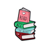 A lapel pin featuring a stack of three enamel books with the word READ ALL and THE BOOKS on them.