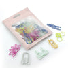 A pink pouch contains a set of colorful decorative bookmarks and paper clips.